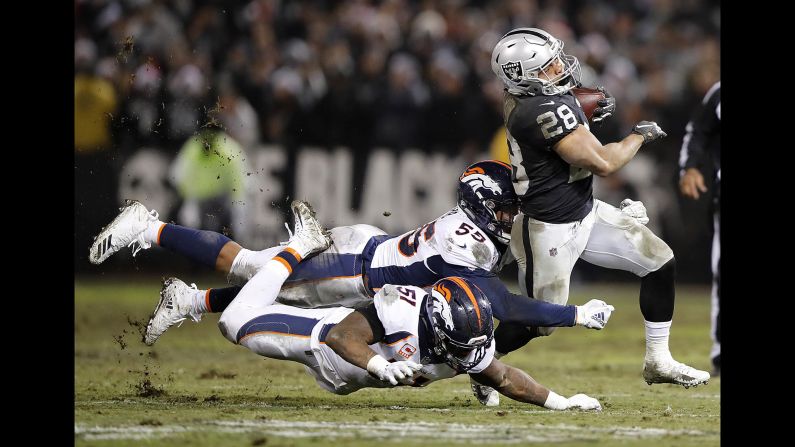 Oakland Raiders running back Doug Martin, right, runs against Denver Broncos outside linebacker Bradley Chubb, left, and inside linebacker Todd Davis during the second half of a game in Oakland, California, on Monday, December 24.