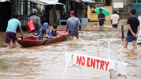 People wade through flooded streets in the town of Baao in Camarines Sur province on December 30.