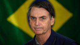 TOPSHOT - Brazil's right-wing presidential candidate for the Social Liberal Party (PSL) Jair Bolsonaro walks in front of the Brazilian flag as he prepares to cast his vote during the general elections, in Rio de Janeiro, Brazil, on October 7, 2018. - Polling stations opened in Brazil on Sunday for the most divisive presidential election in the country in years, with far-right lawmaker Jair Bolsonaro the clear favorite in the first round. About 147 million voters are eligible to cast ballots and choose who will rule the world's eighth biggest economy. New federal and state legislatures will also be elected. (Photo by Mauro PIMENTEL / AFP)        