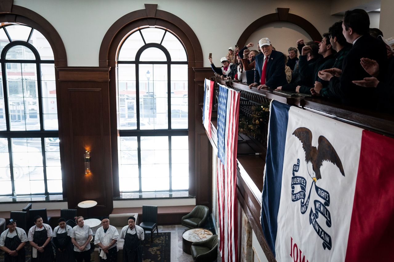 Former president Donald Trump stands with volunteers and unfurls an American flag at Hotel Fort Des Moines in Des Moines, Iowa on Sunday, January 14.