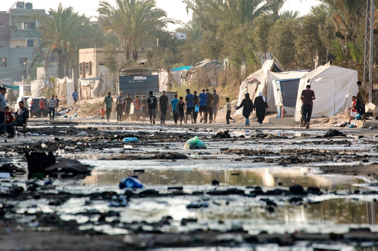 People walk along a street covered with stagnant wastewater in Deir el-Balah, Gaza, on Friday.