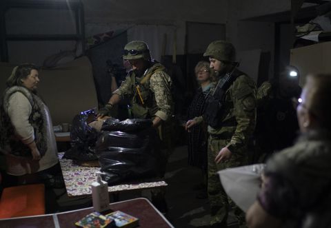 Ukrainian special task force police officers deliver bread to people living inside a basement bomb shelter in Severodonetsk, Ukraine on Friday, May 13.