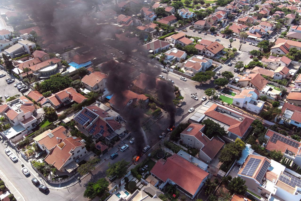 An aerial view shows vehicles on fire as rockets are launched from the Gaza Strip, in Ashkelon, southern Israel, on October 7, 2023.