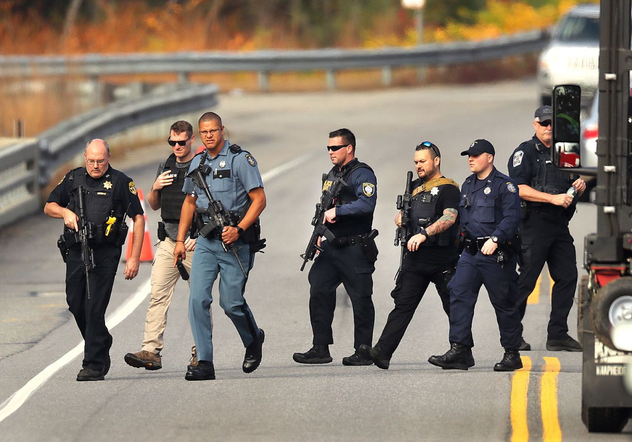 Heavily armed police walk near near the boat launch near the Androscoggin River where suspect Robert Card abandoned his car.