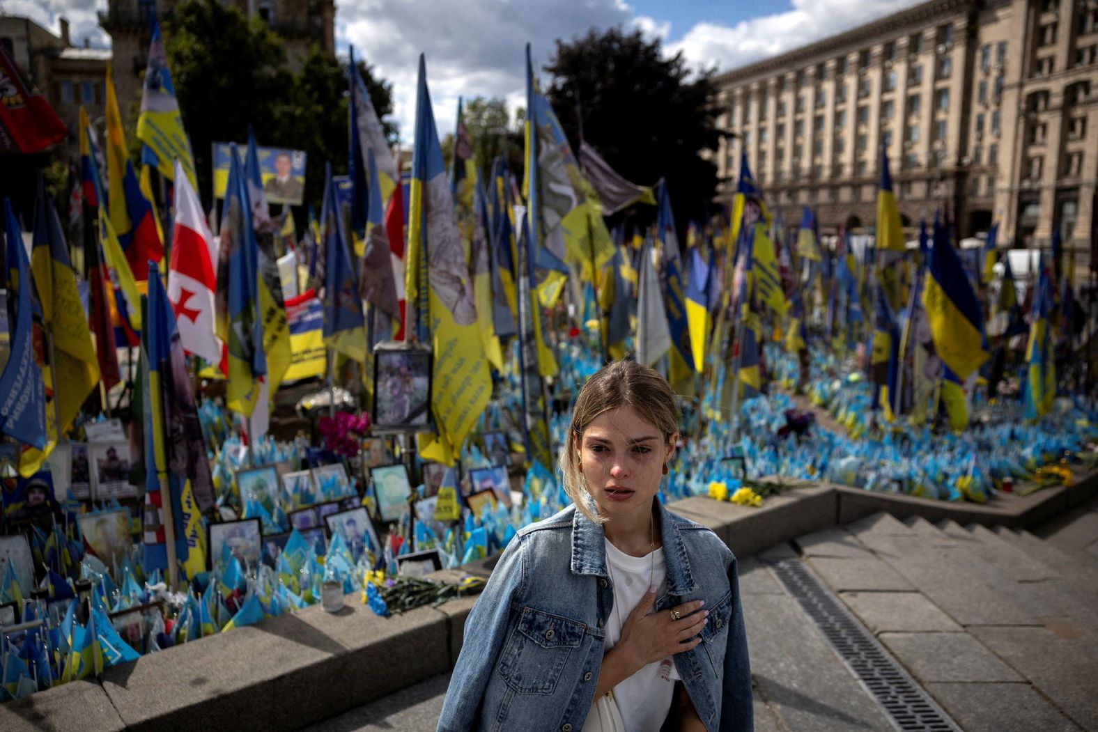 Arina Yevhiienka takes a knee to pay her respects to a fallen Ukrainian soldier as she watches his funeral procession in Kyiv, Ukraine, on Monday, August 25.