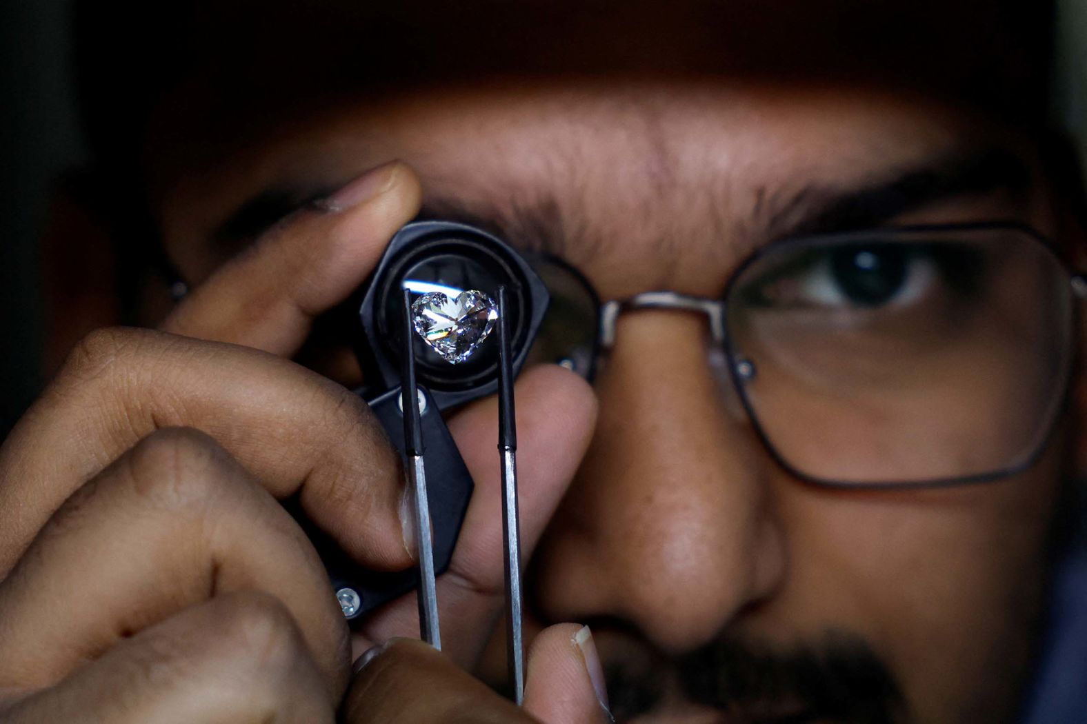 A craftsman checks the grading of a polished diamond in Surat, India, on Friday, August 15.