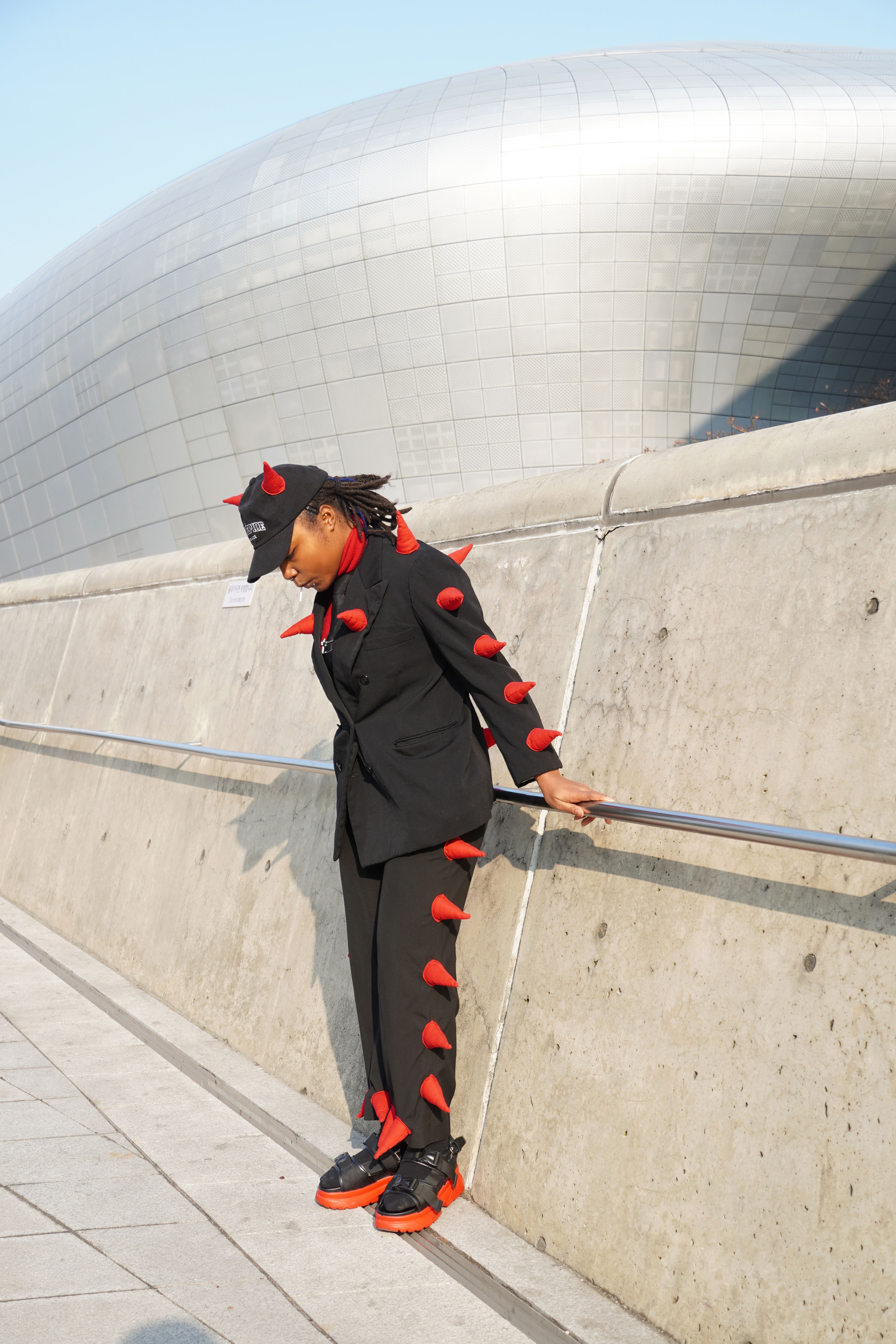 An attendee in an eye-catching black suit and a pair of platform sandals.