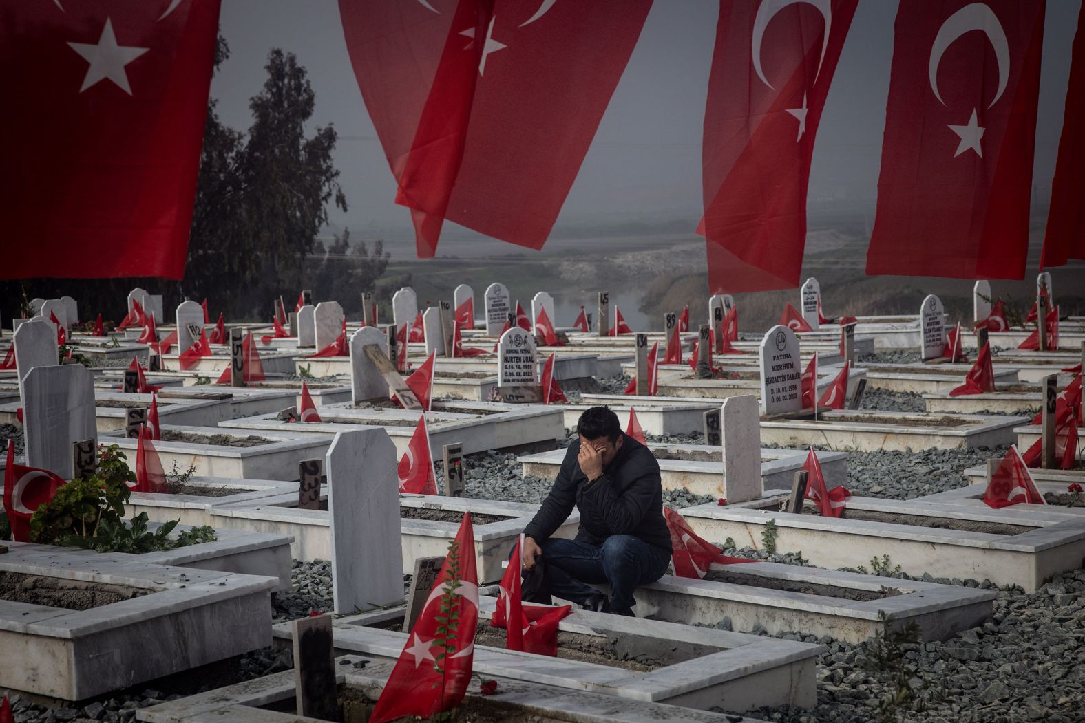 A man in Hatay, Turkey, sits in a cemetery on Tuesday, February 6, mourning a loved one who was killed in an earthquake last year. <a href="index.php?page=&url=http%3A%2F%2Fwww.cnn.com%2F2023%2F02%2F06%2Fworld%2Fgallery%2Fearthquake-turkey-syria-2023%2Findex.html">The earthquake</a> killed more than 50,000 people in Turkey and thousands more in neighboring Syria.