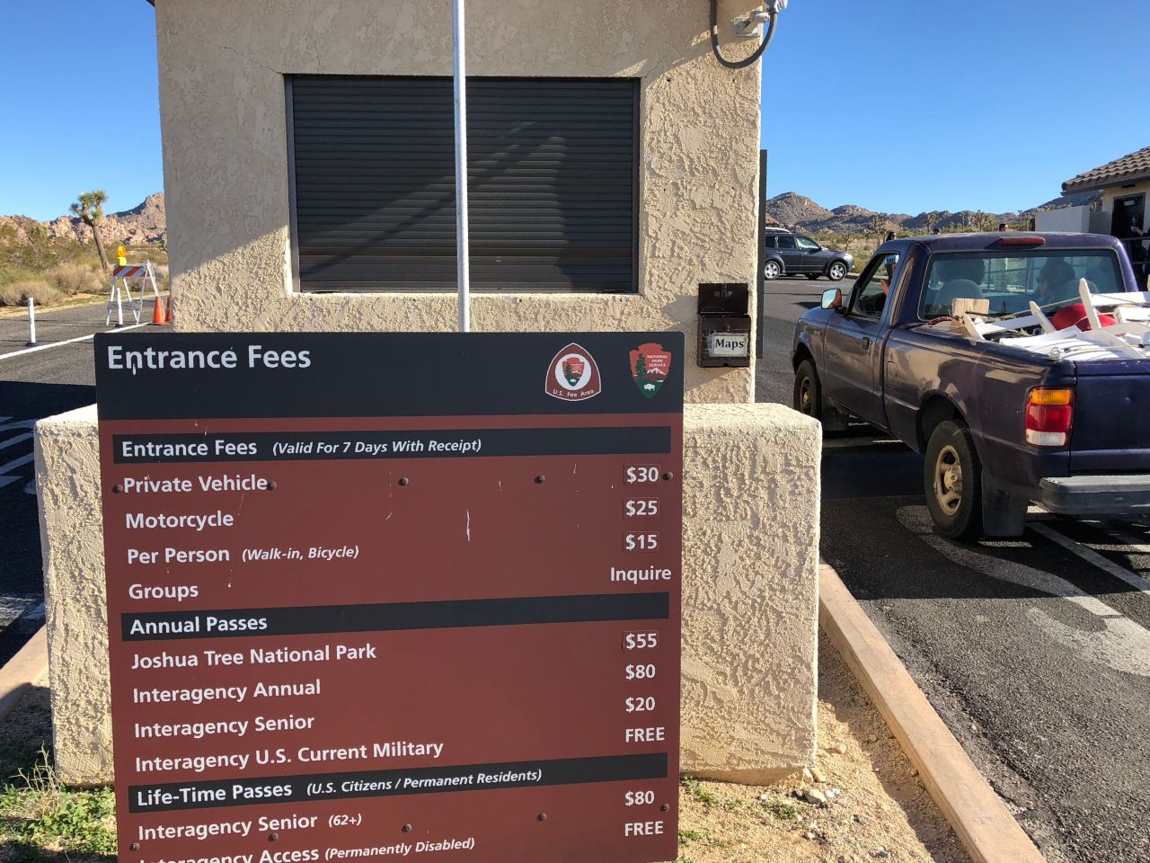 A car drives into Joshua Tree National Park in California past a shuttered entrance station.