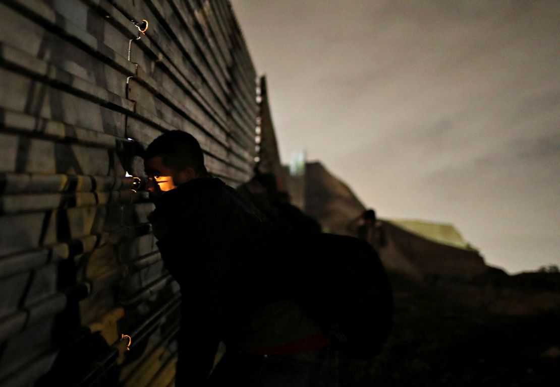 A man looks through the fence as he and others prepare to cross it illegally on Monday.