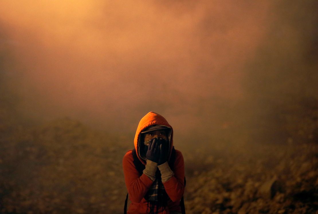 A migrant, part of a caravan of thousands from Central America trying to reach the United States, covers his face after U.S. Customs and Border Protection (CBP) throw tear gas to the Mexican side of the fence as they prepared to cross it illegally, in Tijuana, Mexico, January 1, 2019.   REUTERS/Mohammed Salem
