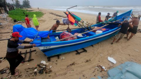 Thai men move a fishing boat to a safer location in Songkhla, southern Thailand, in preparation for storm weather conditions on Thursday.