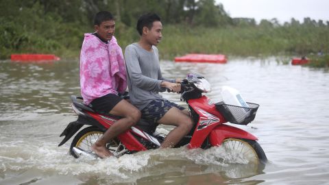 Thai men ride a motorcycle Friday through floodwaters from Tropical Storm Pabuk in the Pak Panang district of Nakhon Si Thammarat province.