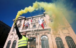 A protester in Marseille holds a flare in front of the town hall.