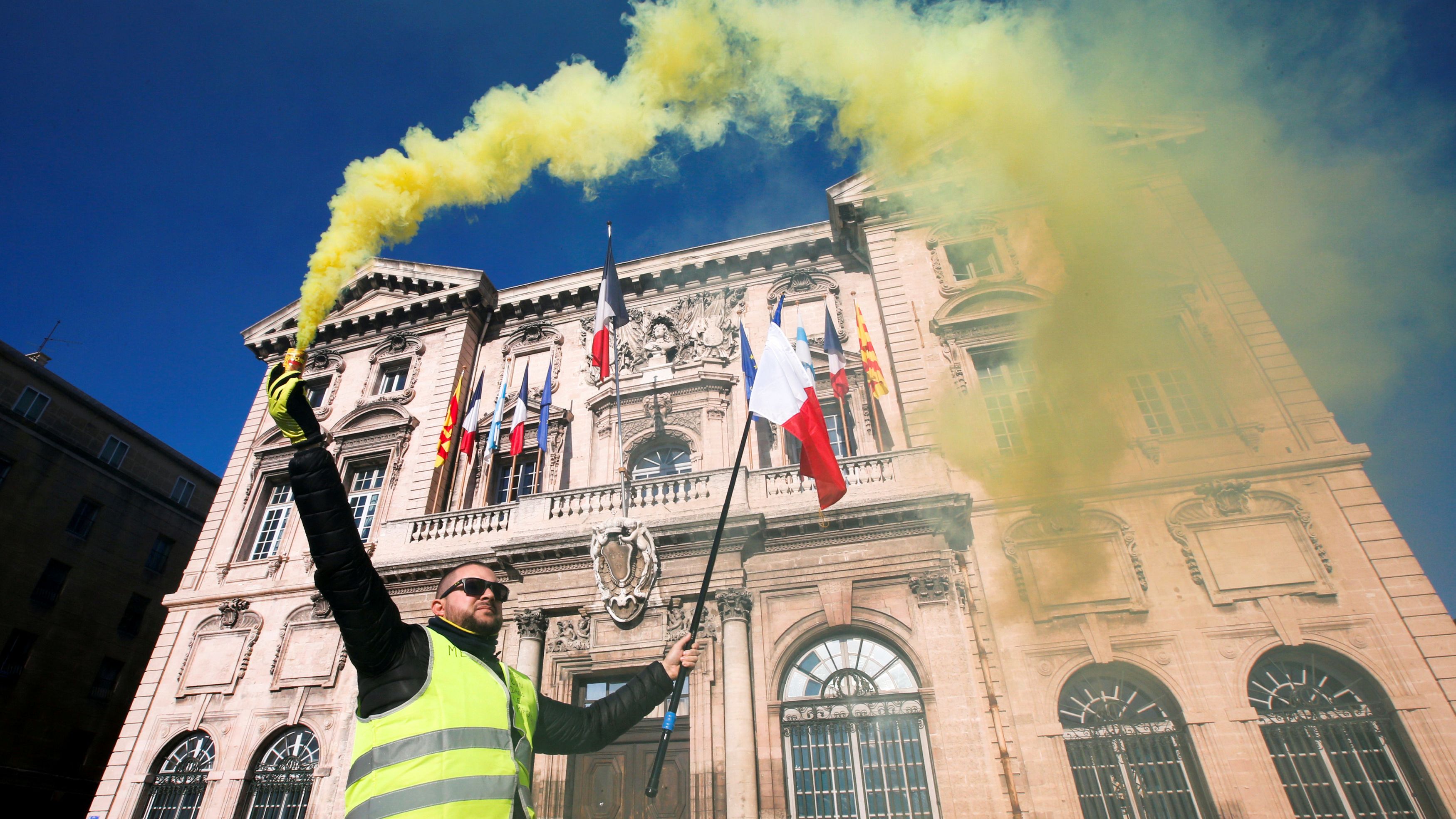 A protester in Marseille holds a flare in front of the town hall.