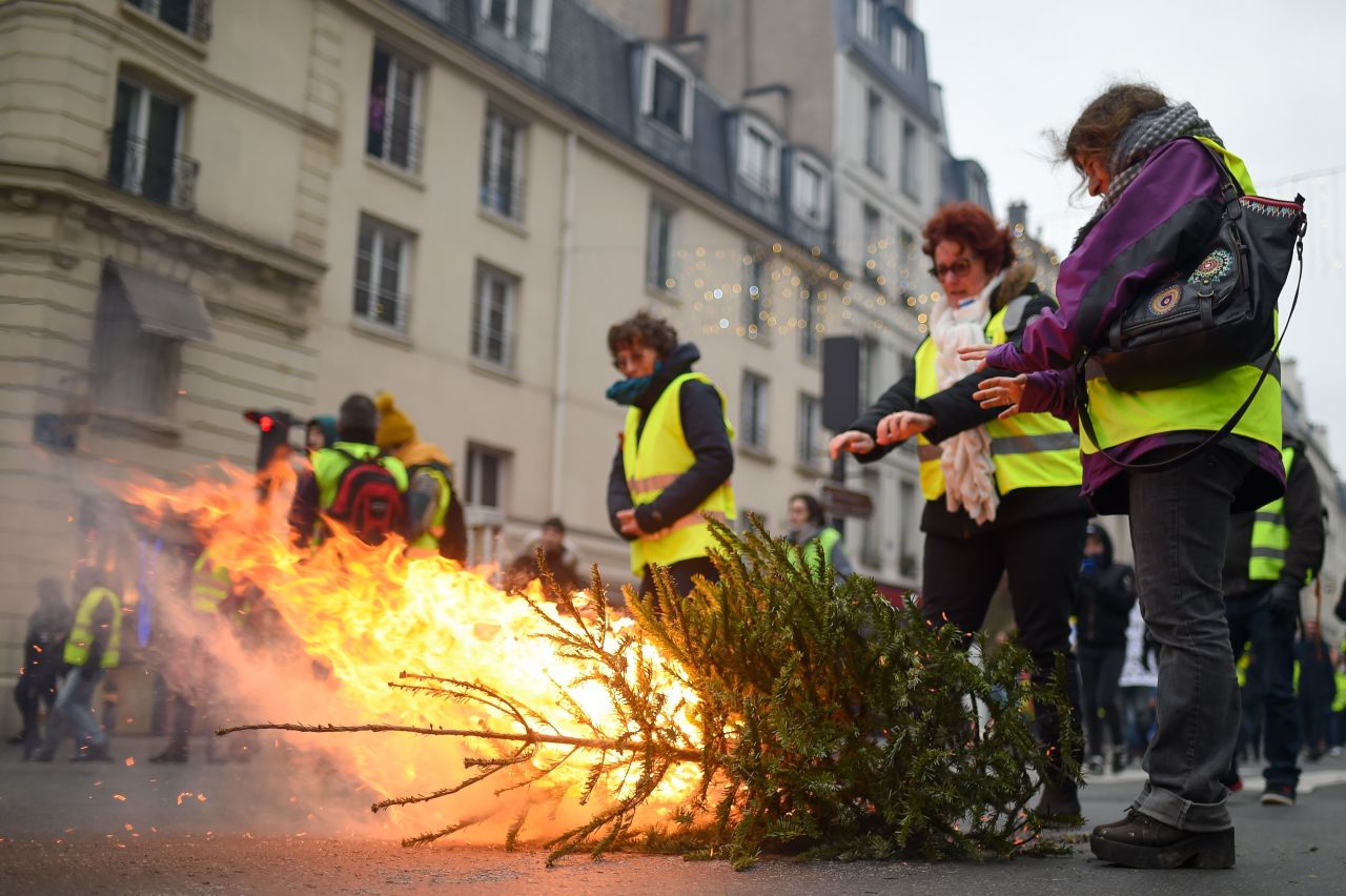 Protesters warm their hands over a burning tree in a Paris street on January 5.