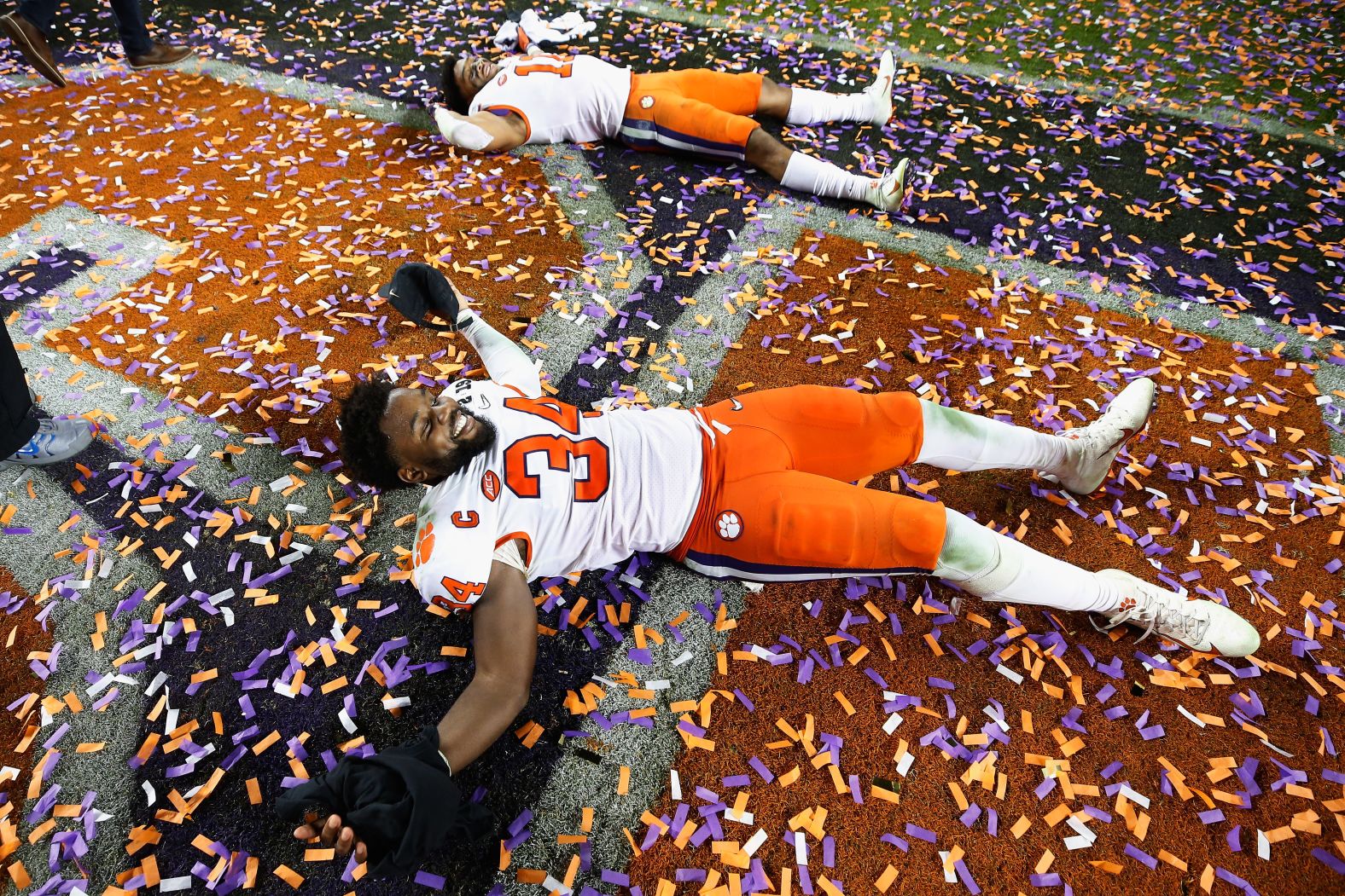 Clemson players make confetti angels on the field.