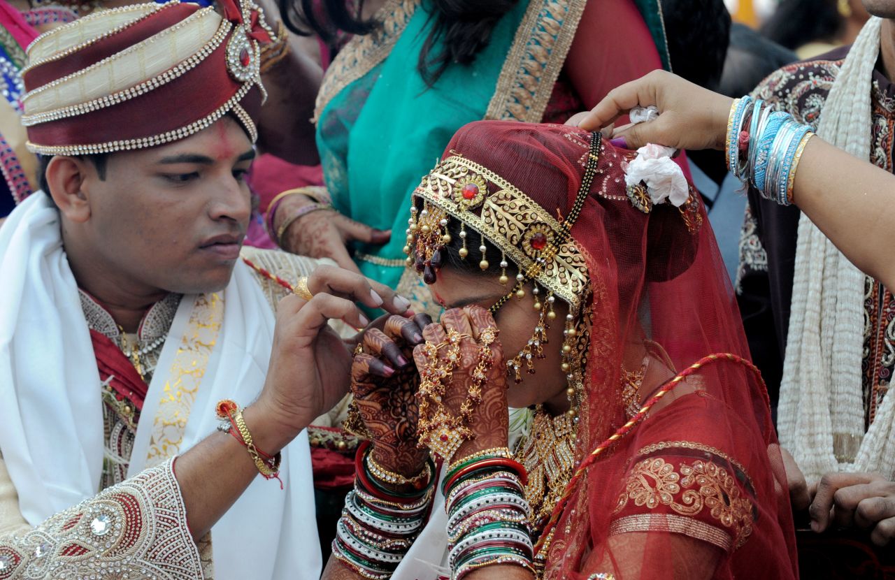 A groom helps his bride with her "mangalsutra," a traditional bridal necklace.