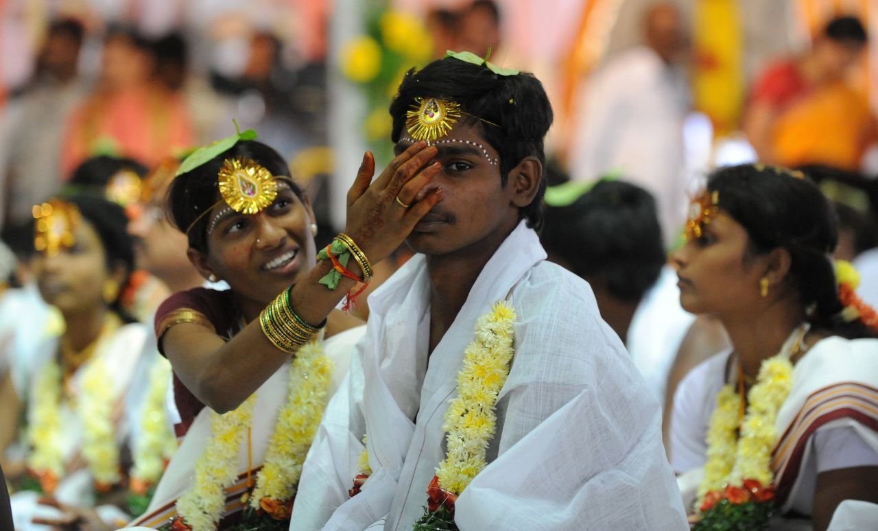 An Indian bride adjusts her groom's headwear during a mass wedding ceremony in Hyderabad.
