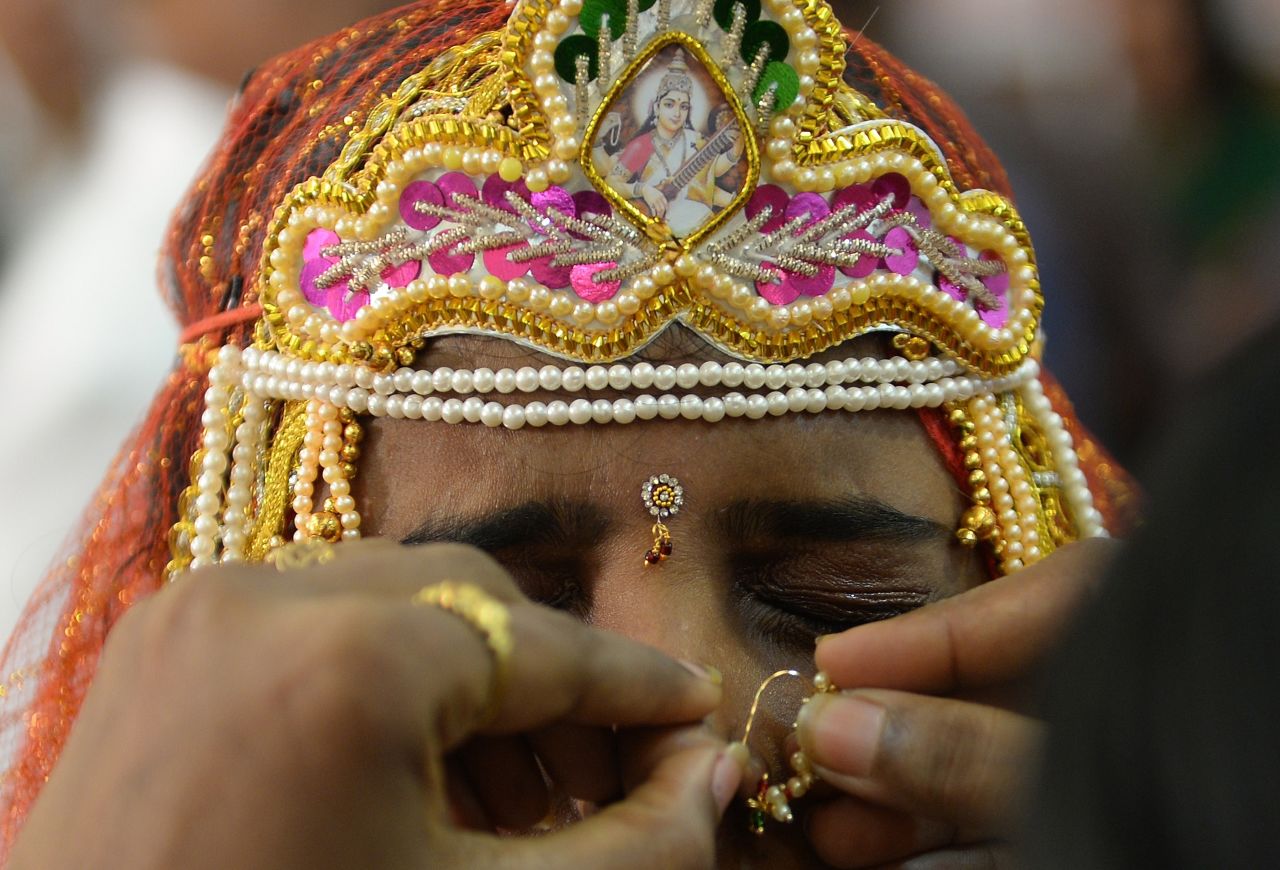 An Indian bride grimaces as a relative adjusts her nose ring during a wedding in Mumbai.