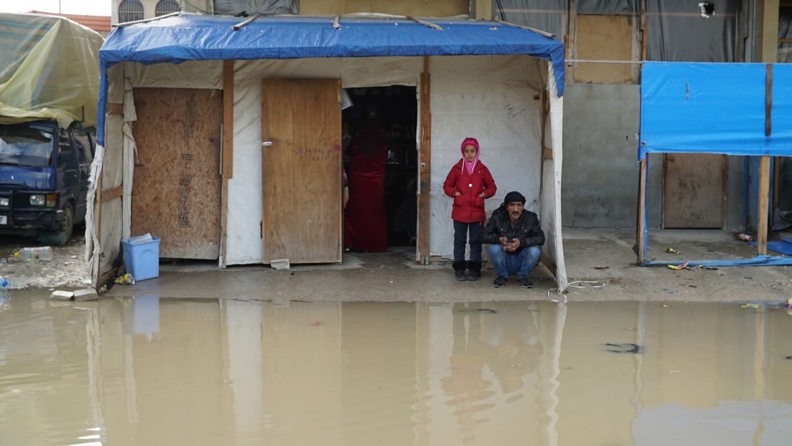 A girl and her father, Syrian refugees, have been living in a corner shop for nearly three years. They woke up on Tuesday to find that they were surrounded by water.