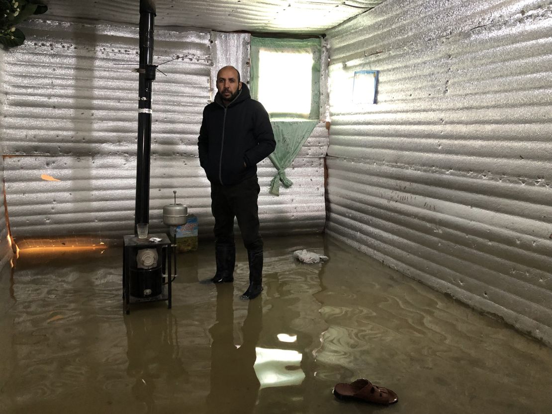 Mohammed Kassaf stands in the living room area of his tarpaulin tent.