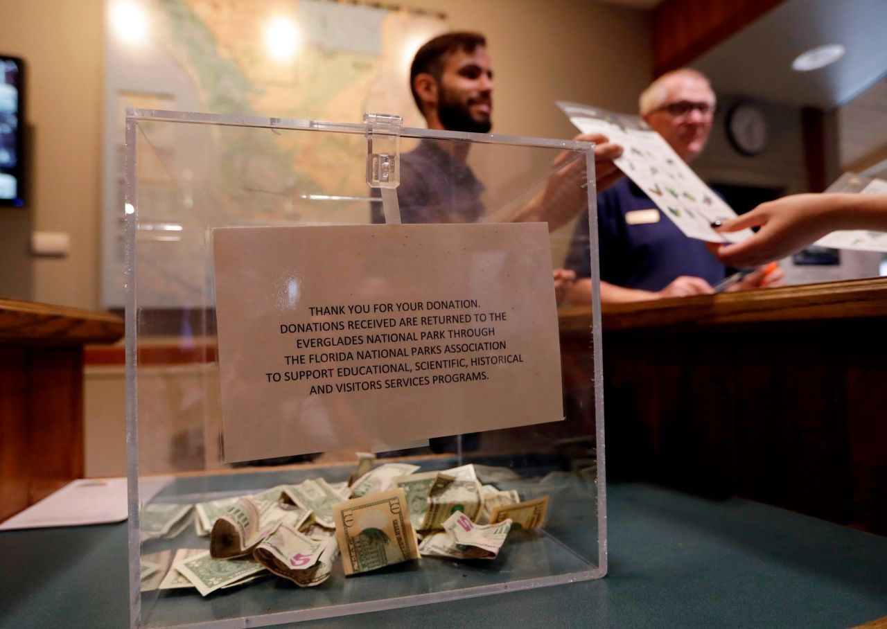 A donation box sits on the counter at the Ernest F. Coe Visitor Center in Florida's Everglades National Park. Dany Garcia, center, was being paid by the Florida National Parks Association to work in the center during the partial government shutdown.