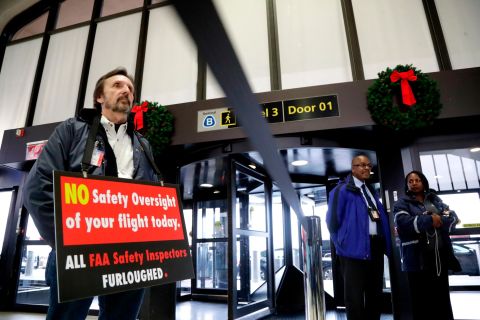 Federal Aviation Administration employee Michael Jessie, who was working without pay as an aviation safety inspector, holds a sign Tuesday, January 8, while attending a news conference at Newark Liberty International Airport in New Jersey. 