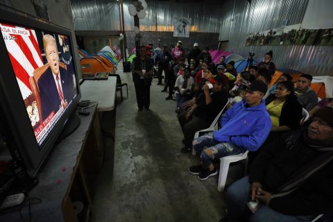 Migrants from Mexico and Central America watch Trump's speech from a shelter in Tijuana, Mexico, on January 8.