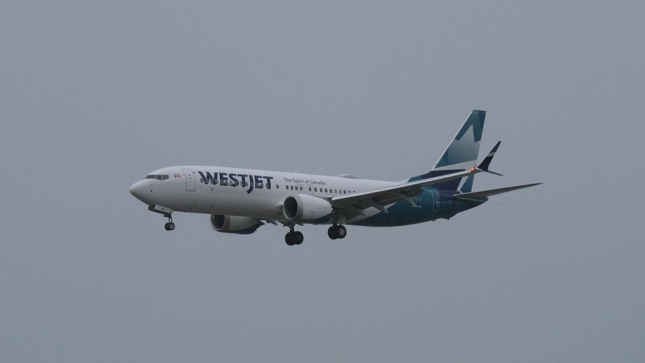 A WestJet 737 appears out of the clouds on short final approach to Vancouver.