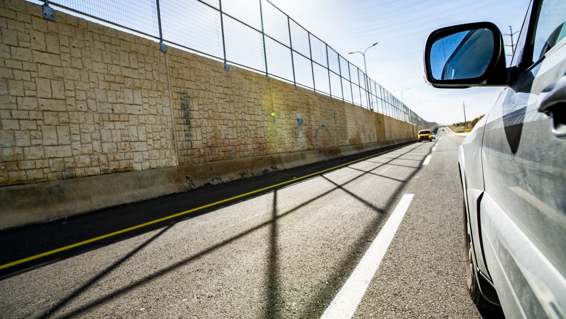 A car drives on the Palestinian side of the road. 