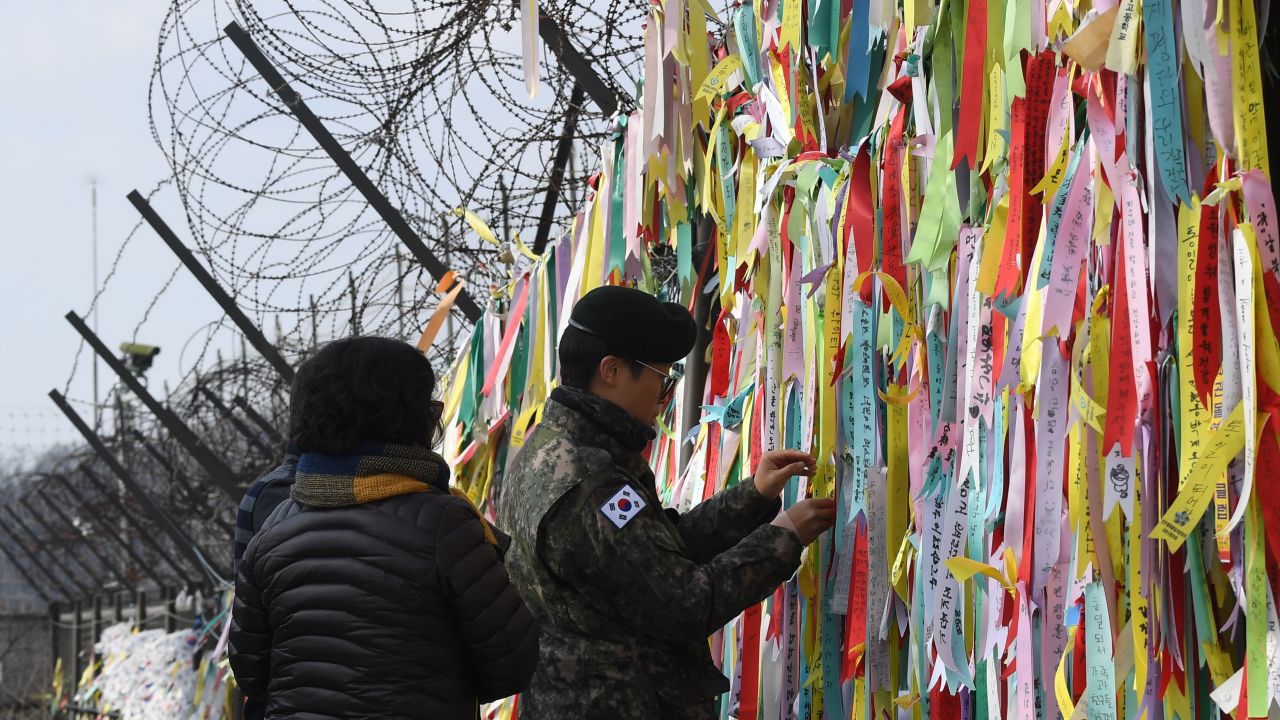 A South Korean soldier looks at ribbons with inscriptions calling for peace and reunification displayed on a military fence near the Demilitarized Zone (DMZ) dividing the two Koreas in the border city of Paju on January 1, 2019.