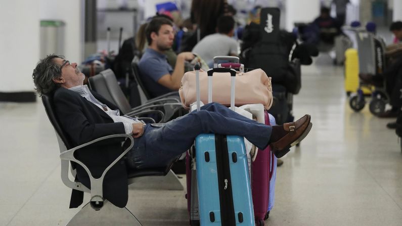 A traveler sleeps near a closed terminal at Miami International Airport on January 12.
