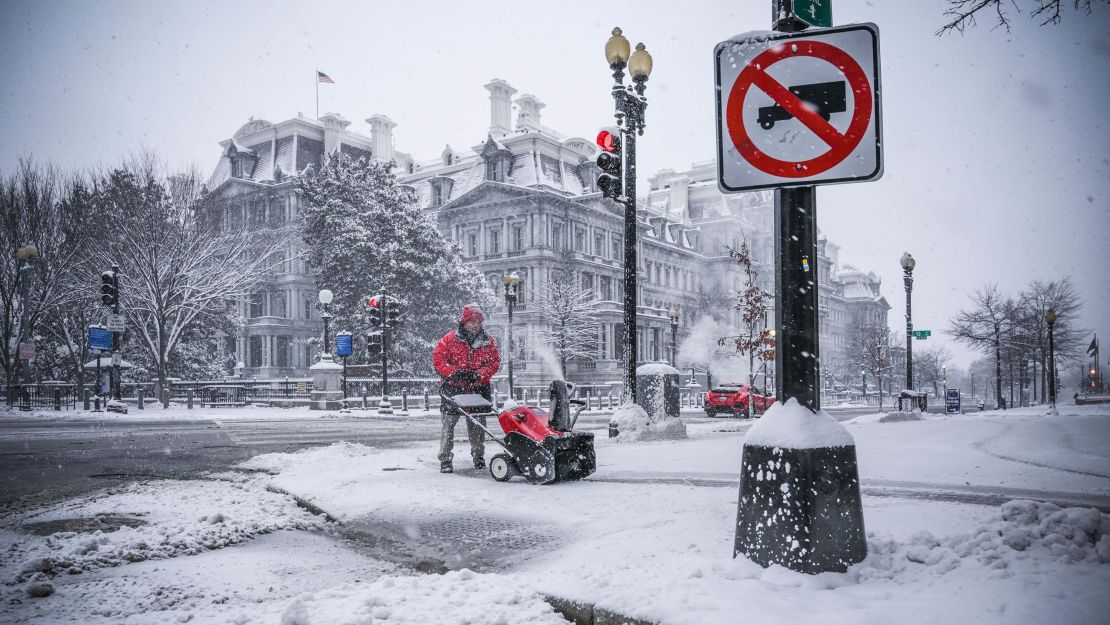 A worker clears Pensylvania avenue next to the White House as snow is accumulating in Washington DC on January 13, 2019.