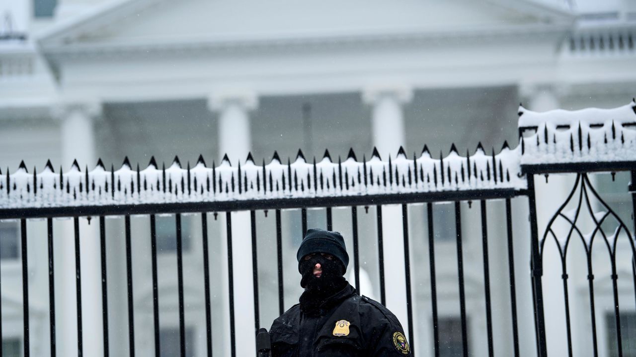 A member of the Secret Service stands guard outside a chilly White House.