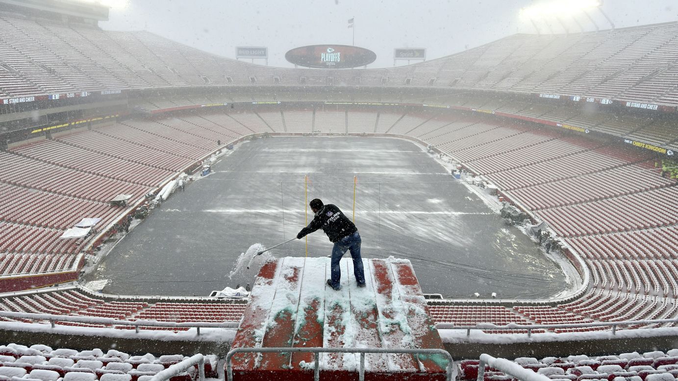 Kyle Haraugh, of NFL Films, clears snow from a camera location at Arrowhead Stadium before an NFL divisional football playoff game between the Kansas City Chiefs and the Indianapolis Colts in Kansas City, Missouri, on Saturday, January 12.