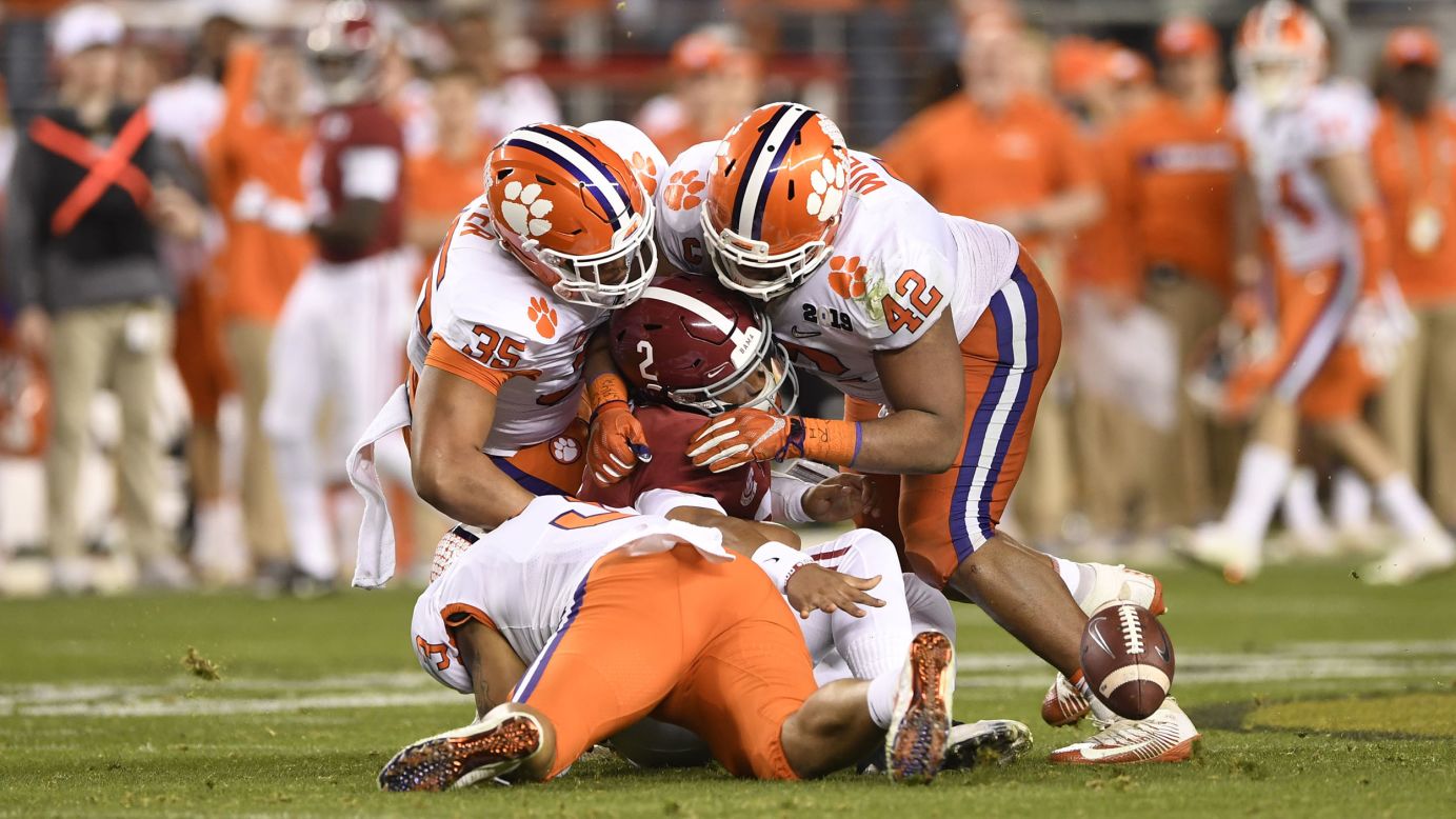 Clemson Tigers defensive tackle Christian Wilkins, defensive end Xavier Thomas and defensive end Justin Foster swarm Alabama Crimson Tide quarterback Jalen Hurts during the second half of the Alabama Crimson Tide's game versus the Clemson Tigers in the College Football Playoff National Championship on January 7.