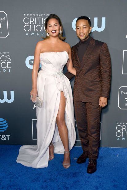 Chrissy Teigen and John Legend attend the 24th annual Critics' Choice Awards. Teigen wore a glamorous ivory gown with a high thigh slit and Legend wore a sharp dark brown suit and turtleneck. 