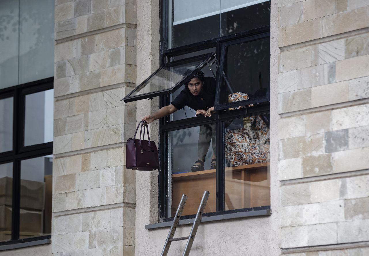 A fleeing civilian throws her handbag before climbing out of a hotel window.