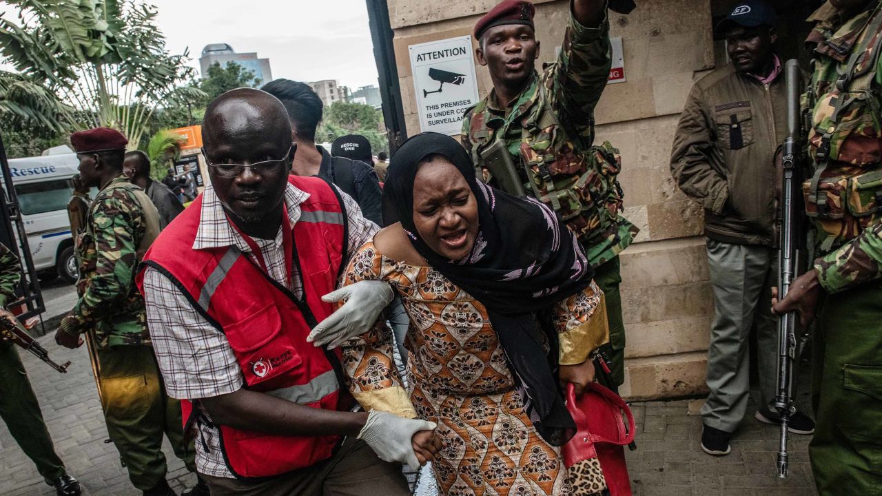 A woman is escorted from the Riverside Drive complex in Nairobi.