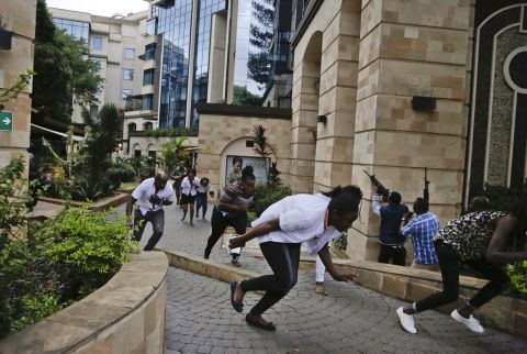 People flee as security forces aim their weapons at the Nairobi hotel complex during the deadly attack January 15.