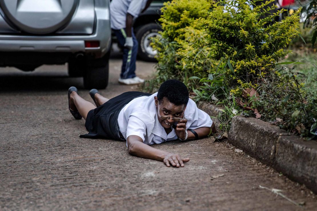 A woman hides behind a car during last week's terror attack at a hotel complex in Nairobi. 
