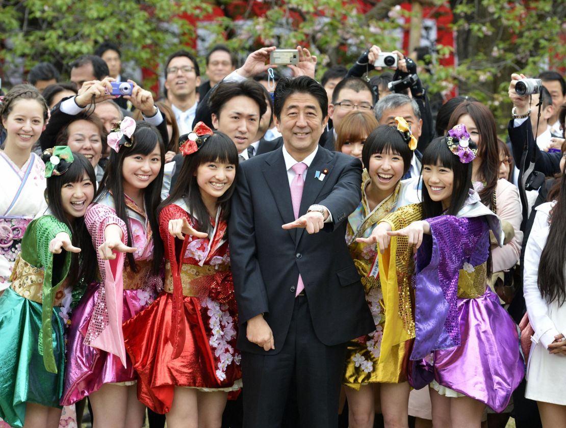 Japanese Prime Minister Shinzo Abe (C front) poses for photos with the five members of girl pop idol group Momoiro Clover Z during the government's cherry blossom viewing garden party in Tokyo on April 20, 2013.