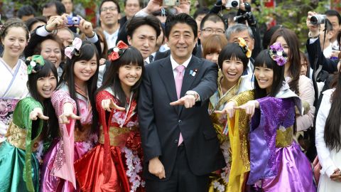 Japanese Prime Minister Shinzo Abe (C front) poses for photos with the five members of girl pop idol group Momoiro Clover Z during the government's cherry blossom viewing garden party in Tokyo on April 20, 2013.