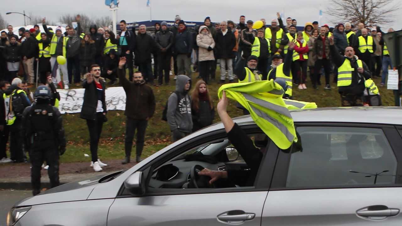 A car driver shows his yellow vest to cheer protesters as French President Emmanuel Macron visits Normandy on Tuesday.