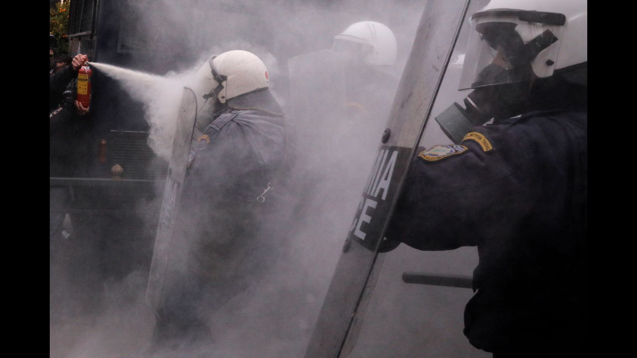 A protester in Athens on Monday, January 14, uses a fire extinguisher against riot police during clashes as Greek schoolteachers demonstrate against government plans to change hiring procedures in the public sector.