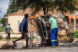 A scrap metal collector salvages sellable parts from a car burned during the protests in Bulawayo on January 17.