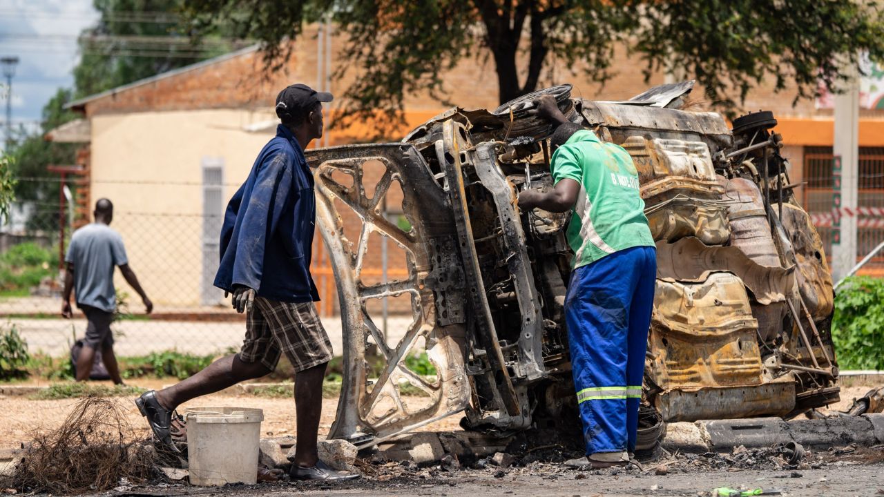 A scrap metal collector salvages sellable parts from a car burned during the protests in Bulawayo on January 17.