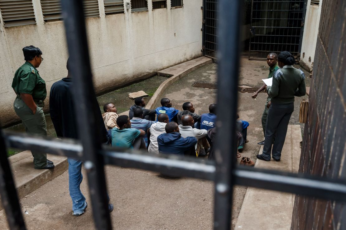 Prison guards watch over men arrested during the protests as they wait for their hearing at the Law Court in Harare on January 16.