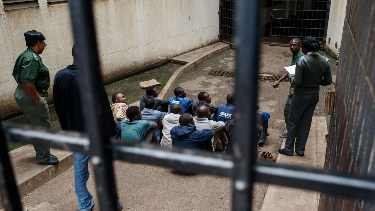 Prison guards watch over men arrested during the protests as they wait for their hearing at the Law Court in Harare on January 16.
